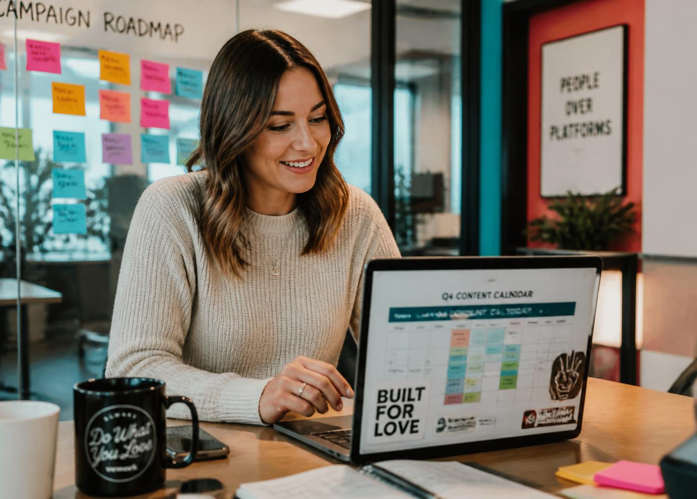 A marketing manager reviewing a colourful content calendar on her laptop